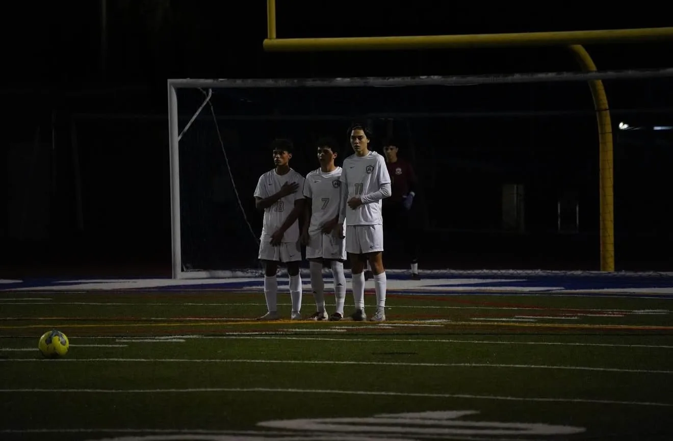 Players lined up in a defensive wall for a free kick during a night match